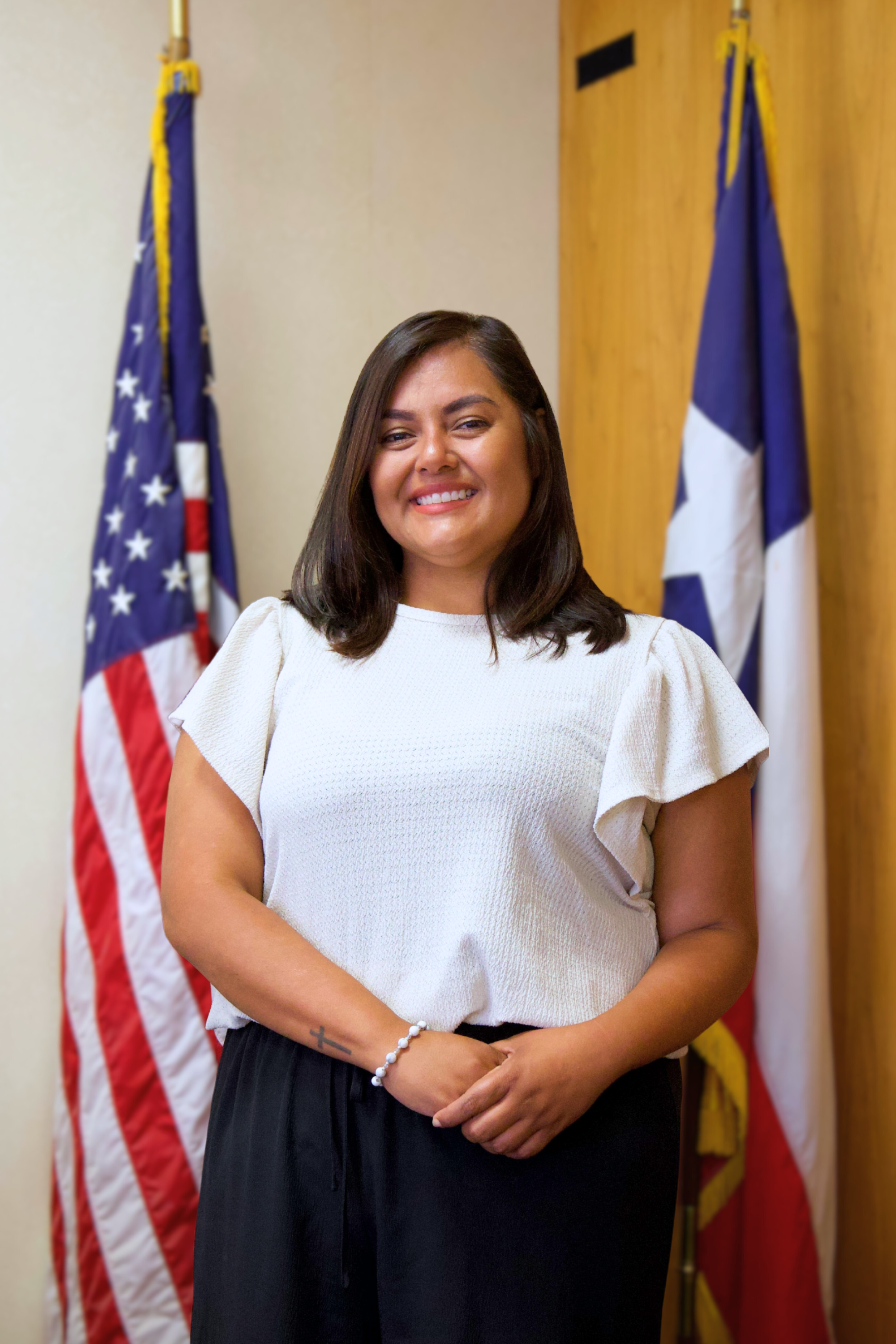 Syra Nichols standing in front of an American and Texas flag.